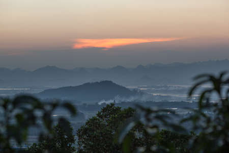 Vietnam scenery in the evening. Foggy landscape with mountains and river in the distance, trees in...