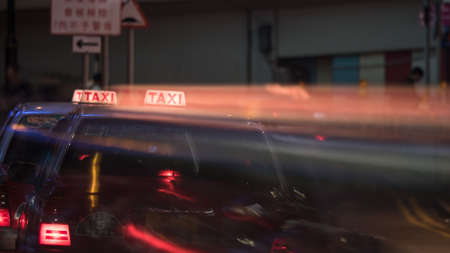 Taxi cars on night road, motion shot with trail from illuminated cab sign. Hong Kongの写真素材