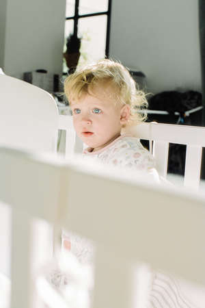 A portrait of a baby girl, freshly awakened and got up in her cot