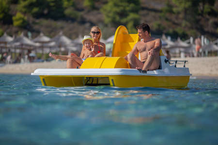 A young family floats on a catamaran in a sea near a beachの写真素材