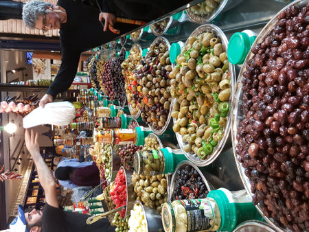 TEL AVIV, ISRAEL - MARCH 11, 2017: At the famous food market Sarona. View with great assortment of olives and buyer getting foodのeditorial素材