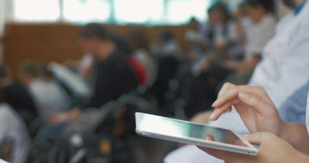 Close-up shot of female hands typing on tablet computer in auditorium during the medical lecture,...