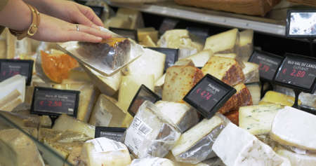 Woman looking over different types of cheeses in the shop. Variety of choice in kinds and prices