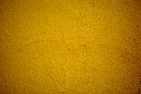 Old grungy ochre colored wall background texture with side vignettes in a full frame view. This is a...