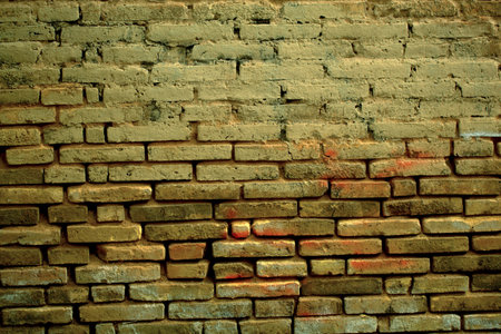 Old weathered clay brick background texture with eroded masonry exposing the bricks in a full frame...