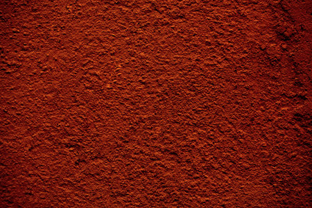 Background texture of a rough finish concrete wall painted in a red brown color in a full frame...