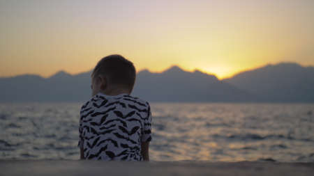 Lonely child on the beach at sunsetの写真素材