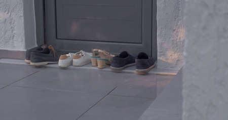 Woman putting on shoes by the houseの写真素材