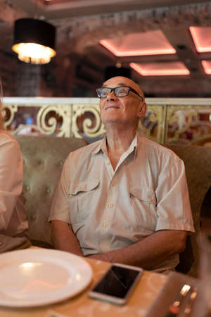 Senior man in restaurant looking at something with interestの写真素材
