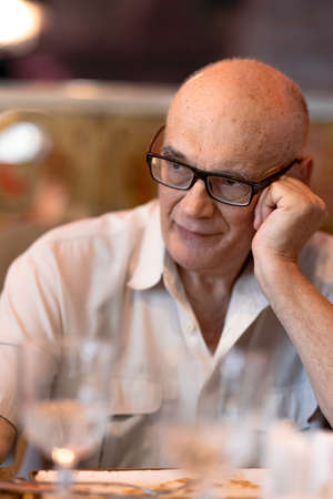 Thoughtful senior man in the restaurantの写真素材