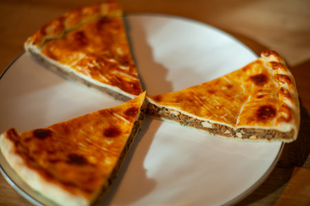 Traditional Russian meat pies sliced and served on a white plate showcasing a golden crustの写真素材
