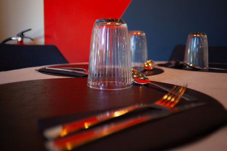 Upside down glass on a dining table with cutlery and place settings in a restaurant setting.