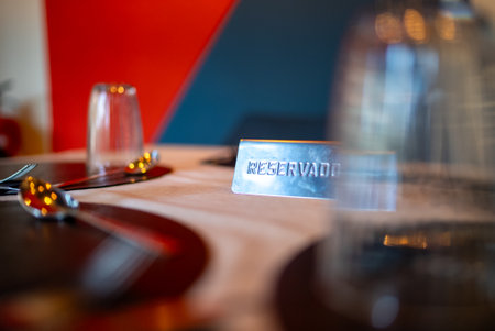 Metal reservado sign resting on an elegantly set restaurant table, marking a reserved dining area,...