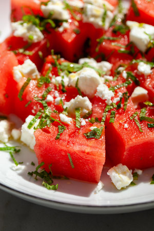 Fresh watermelon salad featuring creamy feta cheese and aromatic mint leaves, beautifully arranged on a plate, offering a delightful and refreshing taste for summer gatheringsの写真素材