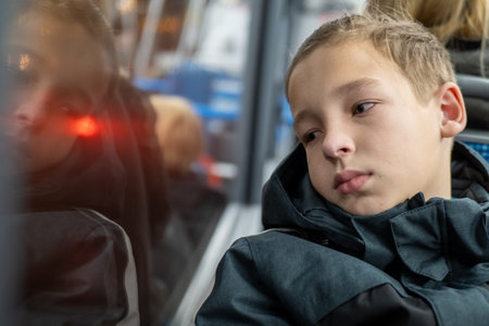 Thoughtful student gazing out the bus window, lost in contemplation during his daily commute to school, reflecting on the journey aheadの写真素材