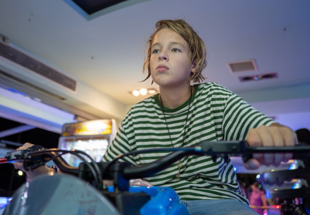 Young boy deeply concentrating while enjoying an exciting arcade motorcycle video game, fully immersed in the thrill of racingの写真素材