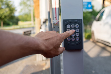 Hand pushing a button on a security keypad, unlocking access to a door or gate, ensuring safety and control for private propertiesの写真素材