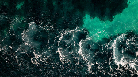 Aerial top view of dark blue sea water and white foam waves crashing along the coast of Vourvourou,...