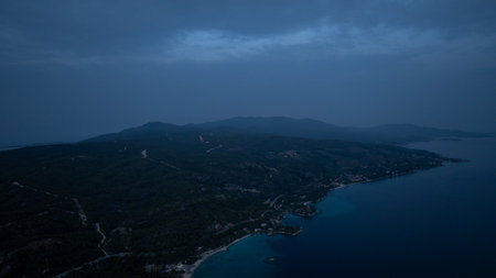 Coastline and mountains fading into darkness at dusk, creating a serene and mysterious atmosphere in Sithonia, Greeceの写真素材