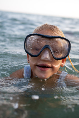 Portrait of a joyful girl wearing a diving mask, swimming playfully in the vibrant sea, embracing the freedom of summer adventuresの写真素材
