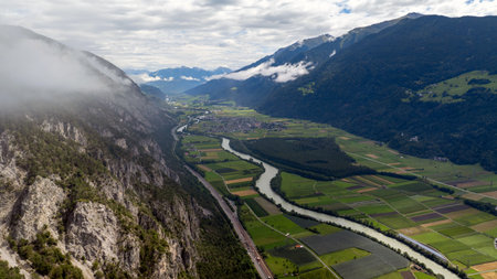 Aerial view of cultivated fields, river inn, highway and railway in the inn valley near Haiming, Tyrol, Austria, with low clouds covering the mountainsの写真素材