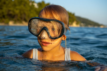 Smiling girl wearing diving mask, swimming through blue ocean waters, experiencing summer freedom and aquatic adventureの写真素材