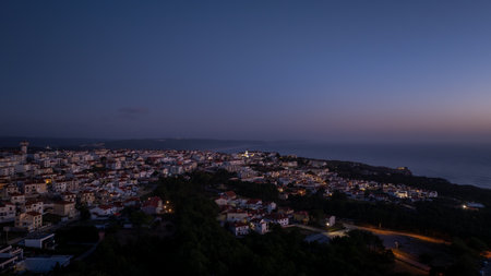 City lights creating a magical glow over Nazare, Portugal, as dusk settles, viewed from a high vantage pointの写真素材