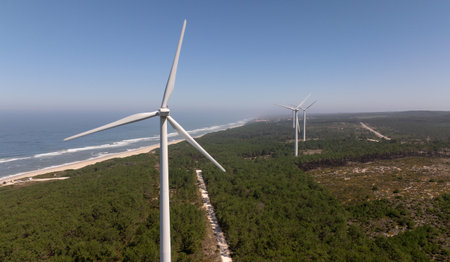 Wind turbines spinning and generating clean energy near the coast of Nazare, Portugal, promoting...