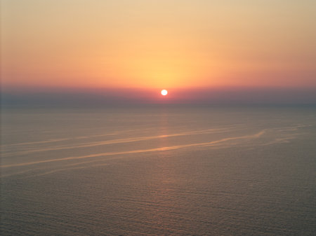 The sun sets over the Aegean sea in Kassandra, Greece, painting the sky with warm colors in a tranquil and beautiful scene perfect for travel and tourismの写真素材