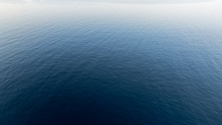 Deep blue water surface gently rippling under a soft light, creating a mesmerizing gradient from dark to light, in Kassandra, Greeceの写真素材