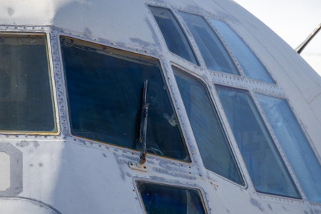 Close-up of cockpit window frame and riveted fuselage showing aging details of preserved aircraft on outdoor displayの写真素材