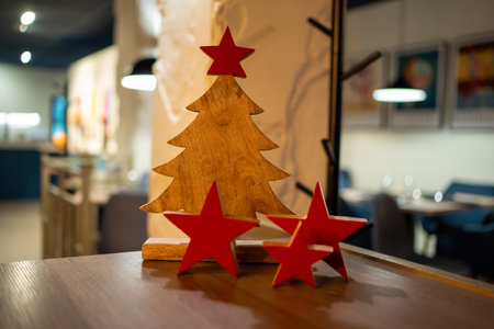 Wooden christmas tree with red stars on a table in a cozy cafe with blurred background lighting