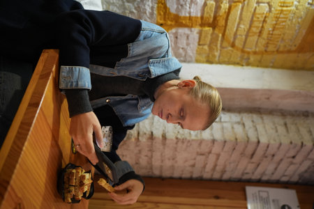 Woman in casual attire focuses on her phone while enjoying a snack and beverage at a cozy cafe