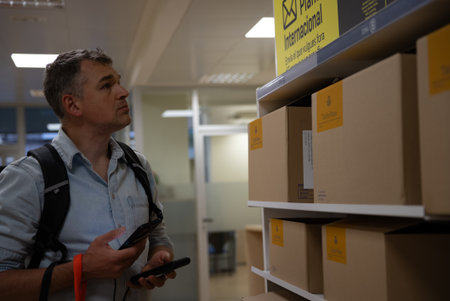 Man with backpack checking labeled cardboard boxes on shelf