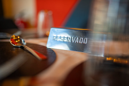 Reserved sign resting on a restaurant table beside a spoon, clearly indicating a booked table....
