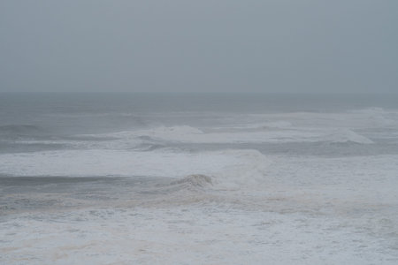 Wide view of powerful white waves breaking in the dark atlantic ocean during a storm under an...