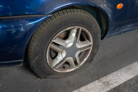 Detailed view of a deflated rubber tire and metal rim on an old blue vehicle