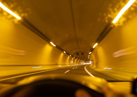 Abstract blurred view of car moving through brightly illuminated yellow highway tunnel
