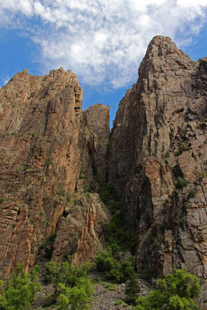 Rock walls tower high overhead, seen from the floor of the Black Canyon of the Gunnison in Colorado.の写真素材