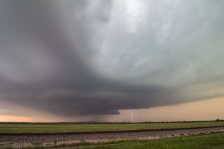 Supercell thunderstorm with lightning strike near sunset.