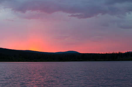 A beautiful pink glowing sunset over a mountain lake.の写真素材