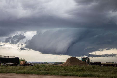 A large gray wall cloud develops with a supercell thunderstorm over the high plains.