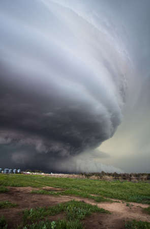 A huge supercell storm with a ground scraping wall cloud towers high over Nebraska farmland.
