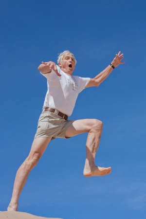 A mature male in his 60s takes a fearful leap into the blue yonderの写真素材