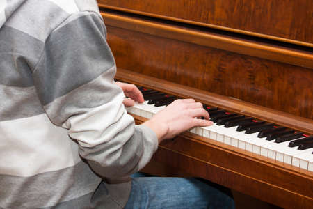A Teen wearing a sweatshirt practices playing the pianoの写真素材