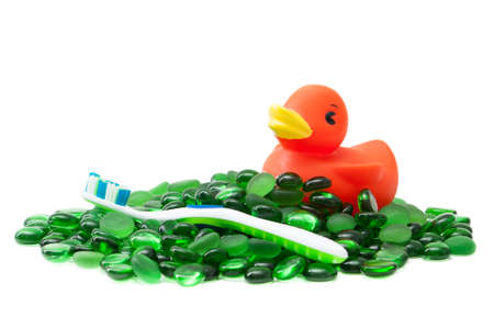 A rubber duckie and toothbrush on a sea of green glass beads isolated on white creates a clean image that says kids bathroom の写真素材