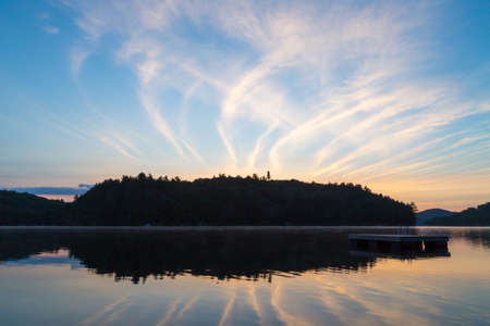 Streaks in the sky relect on the lake as the sun rises over the Narrows of Lake of Bays in Muskoka...