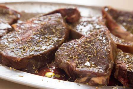 locally hunted platter of venison steaks marinating in herbs and oil before cooking