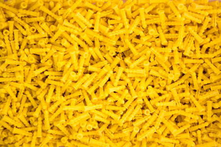 wholesale bin of yellow drywall anchors makes good background for construction and building related themesの写真素材
