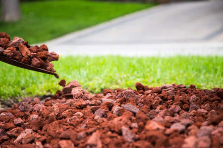 making a new garden with red lava rock. shallow depth of field on the lava stone at the thirds line leaves soft focused background for copy.の写真素材